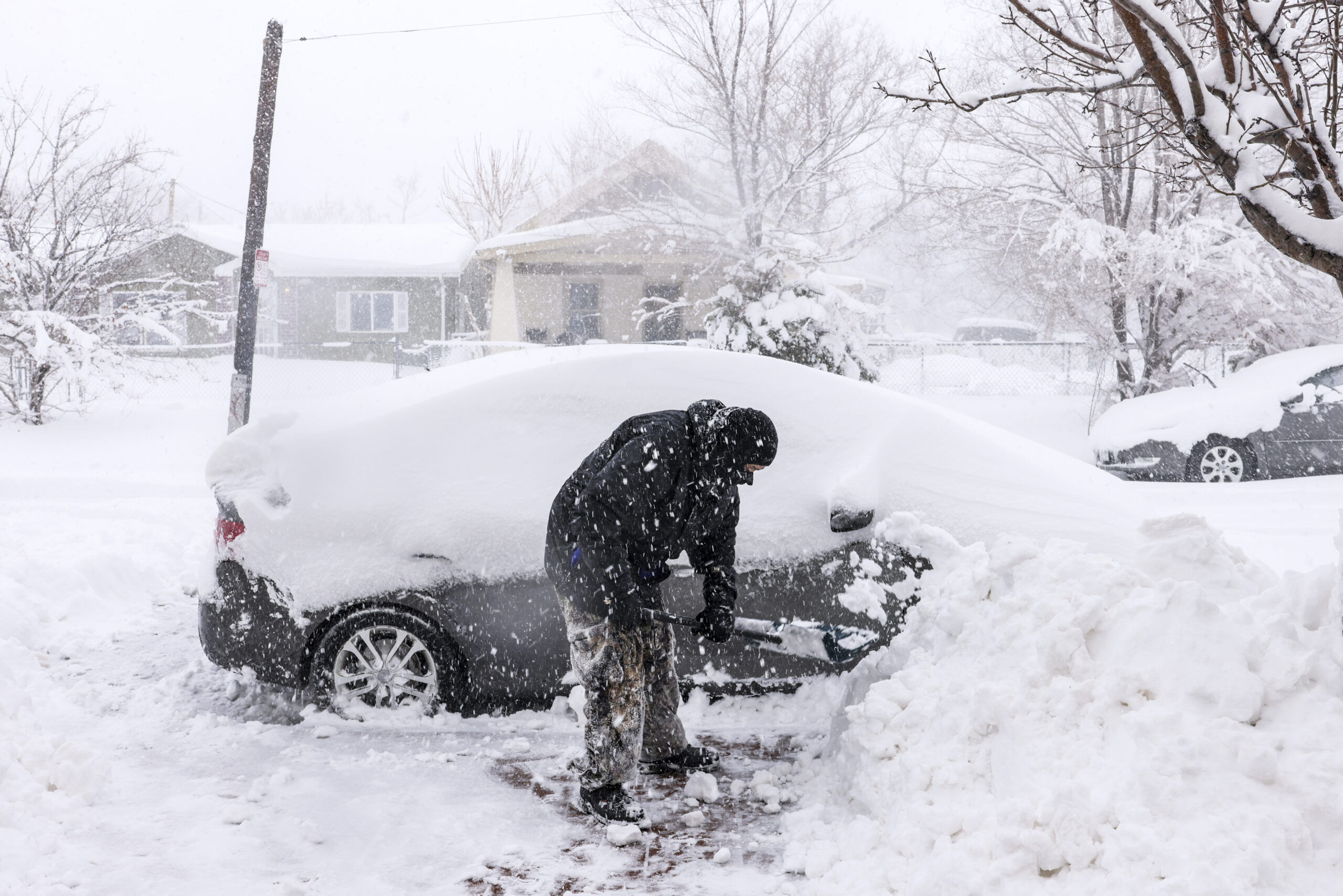 DENVER, CO - MARCH 14: William Freeman shovels the sidewalk next to a car buried in snow on March 1...