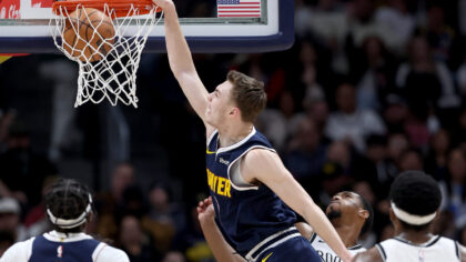DENVER, COLORADO - DECEMBER 14: Christian Braun #0 of the Denver Nuggets dunks on Armoni Brooks #13...
