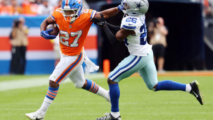 DENVER, COLORADO - OCTOBER 26: J.K. Dobbins #27 of the Denver Broncos stiff arms DaRon Bland #26 of...