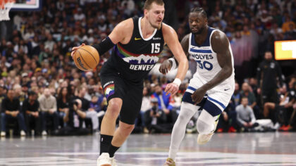 DENVER, COLORADO - DECEMBER 25: Nikola Jokic #15 of the Denver Nuggets drives past Julius Randle #3...