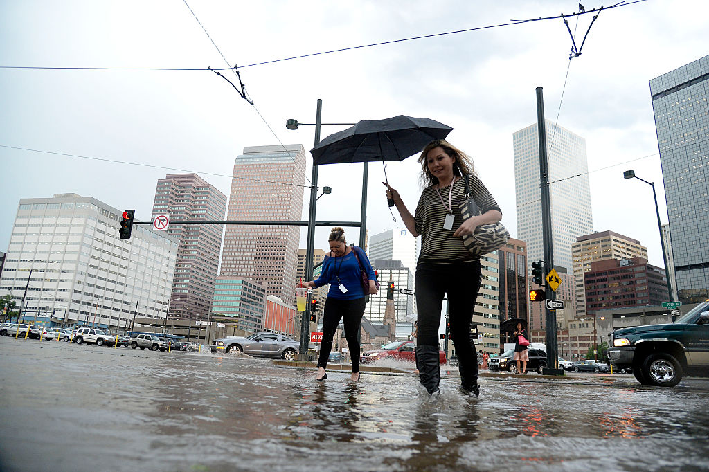 DENVER, CO - JUNE 24: Pedestrians battled the wind, rain and flooded streets as as they cross the s...